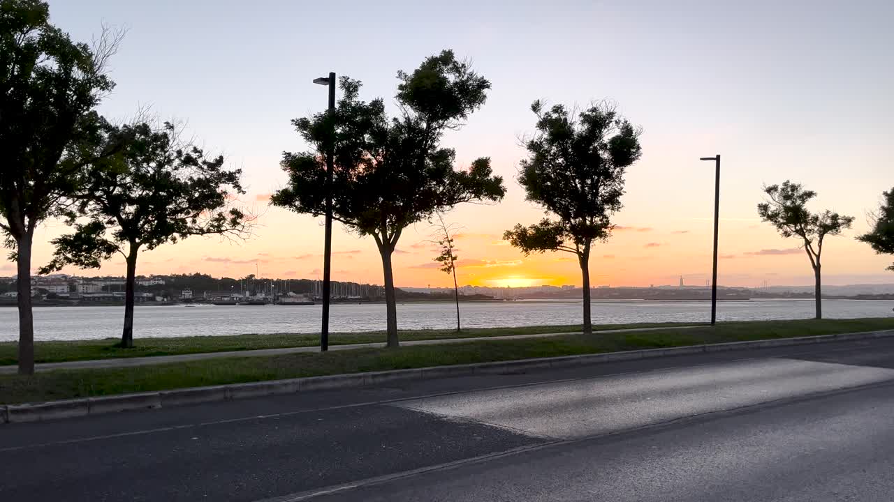 una impresionante vista de la puesta de sol a lo largo de la orilla, con árboles en silueta contra el cielo vibrante. los colores cálidos del sol que se desvanece detrás del horizonte crean una escena tranquila y pintoresca.