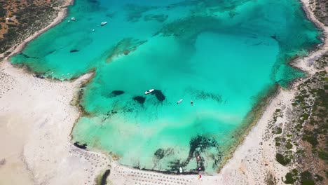 aerial top down spinning overbalos beach and lagoon with turquoise water, mountains and cliffs in crete, greece