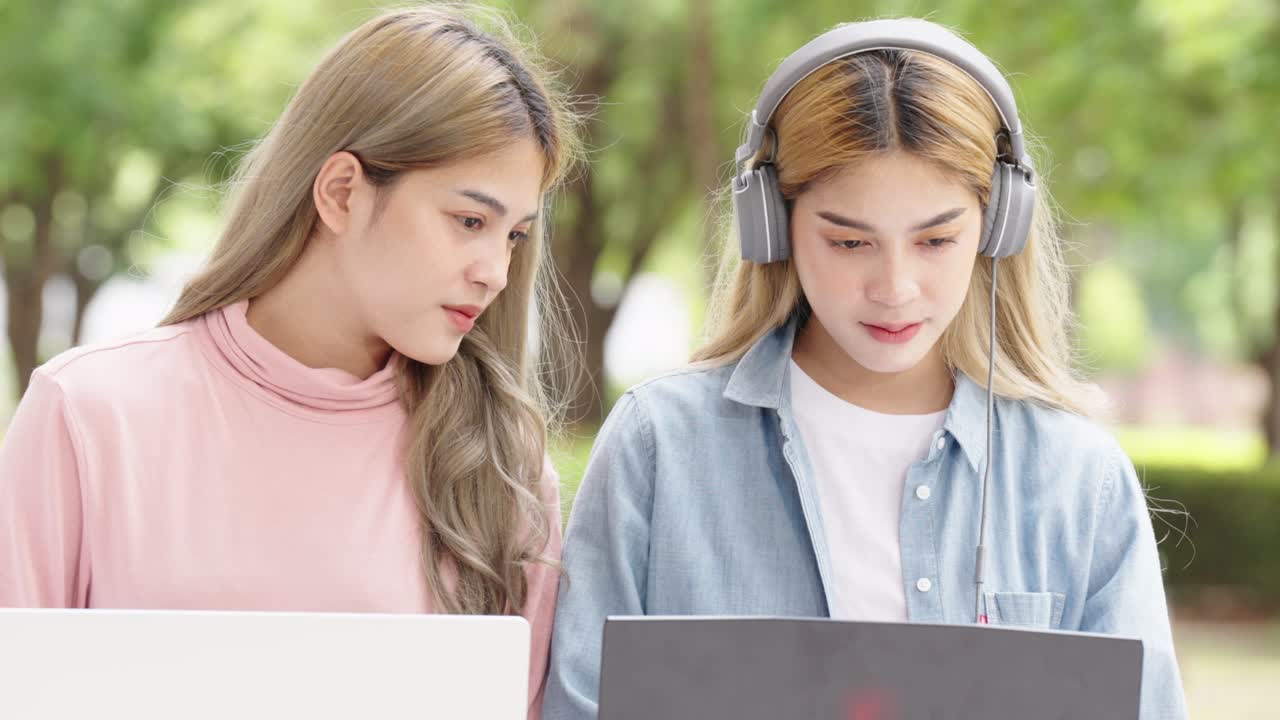 Two Asian girls student partners are working on a laptop help study together