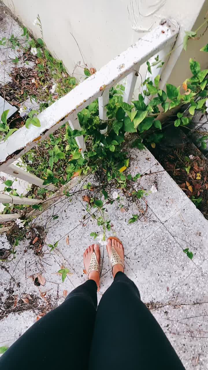 Woman's feet on old concrete steps with plants and railings