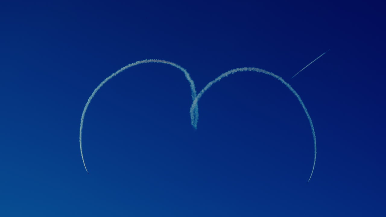 Aerobatic airplanes drawing a heart in the sky