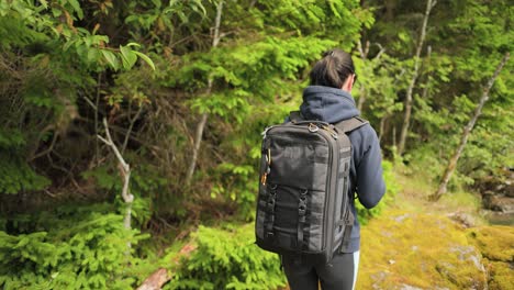 Hiking-woman-walk-with-a-hiking-backpack-in-spring-green-forest