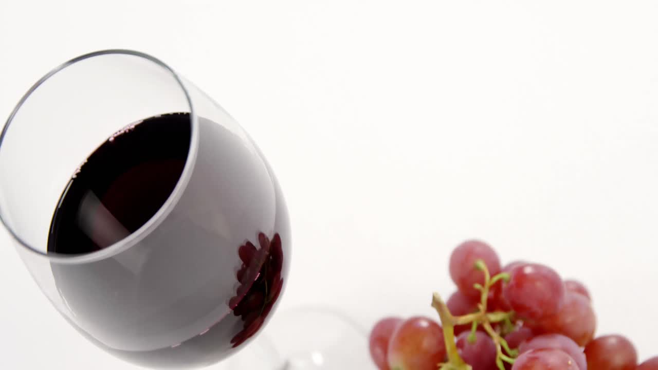 Primo piano di grappolo d'uva rosso con bicchiere di vino rosso
