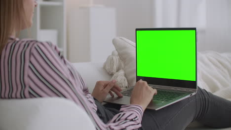 estudiante está chateando en línea por portátil con pantalla verde para la tecnología de clave de croma descansando en casa los fines de semana