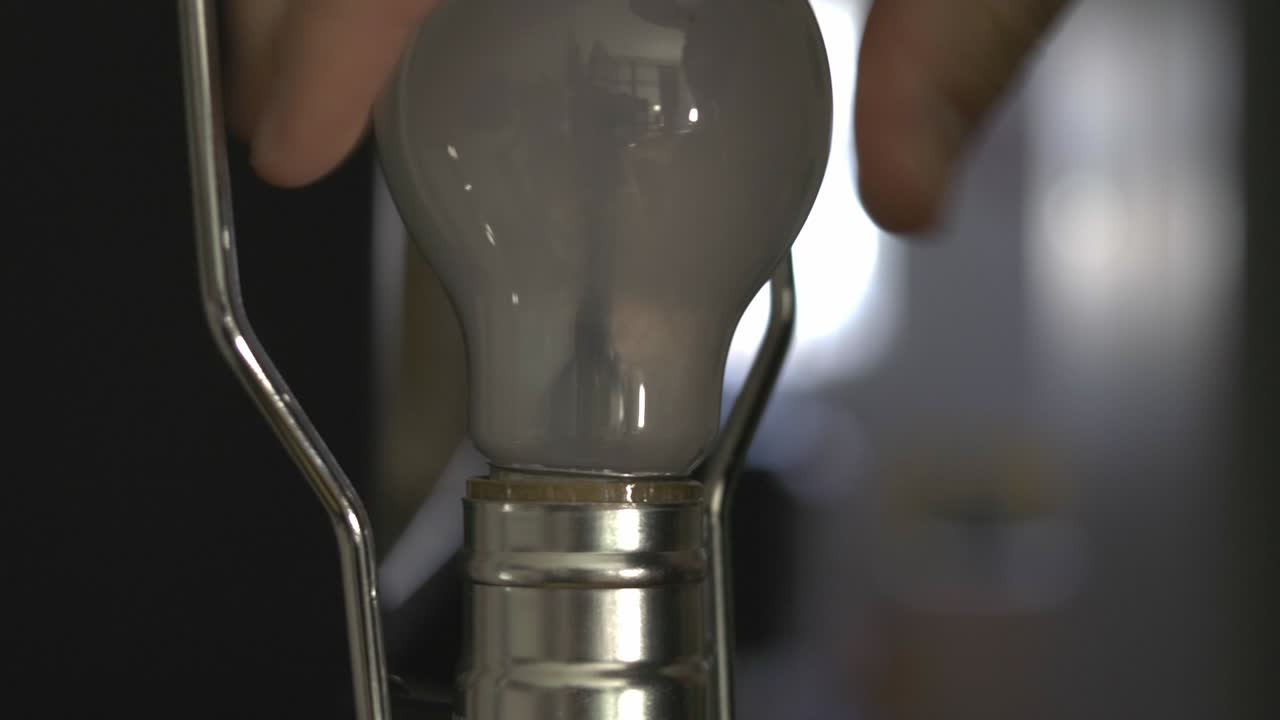 Hand Removing Lightbulb From The Socket - closeup shot