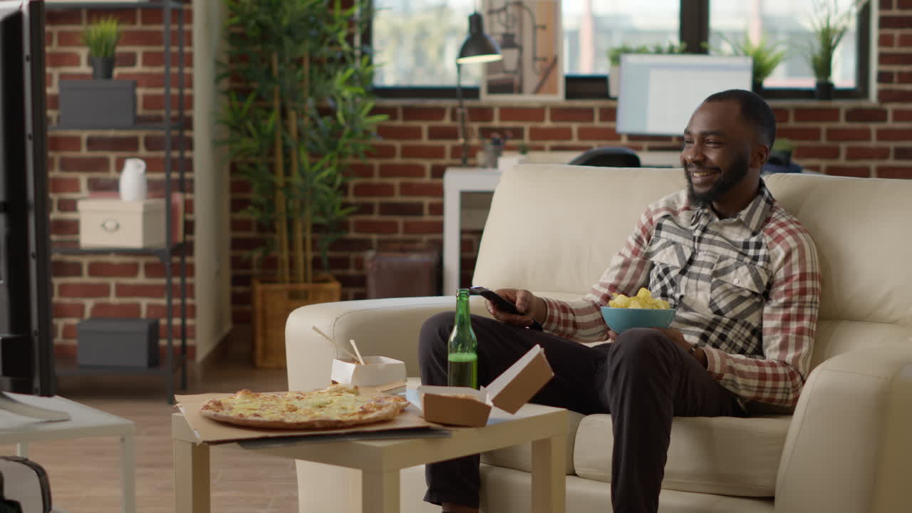 Smiling person holding bottle of alcohol eating chips