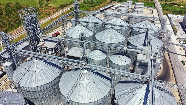 Silos per cereali e macchinari in un impianto di stoccaggio di giorno vicino a una ferrovia