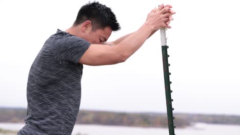 asian male leans on pole