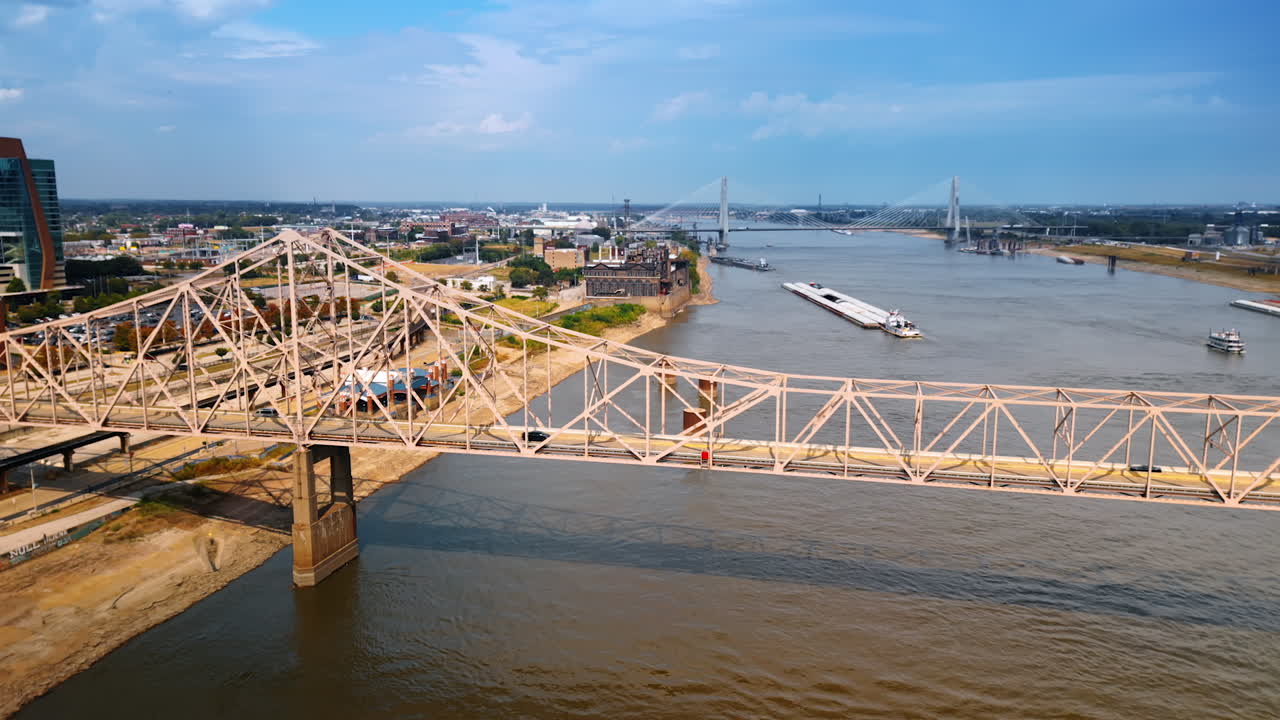 Few cars ride by the Martin Luther Bridge in St. Louis, Missouri, USA. View on the boats on the Mississippi River and some cityscape