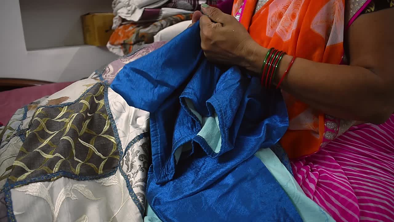 creando una mujer rasgando una vieja sábana azul para hacer cortinas para su casa.