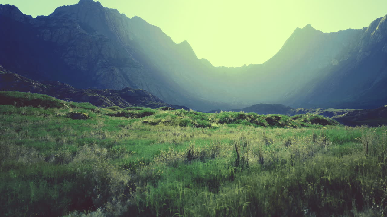 Majestic mountains surround a serene green valley at sunrise