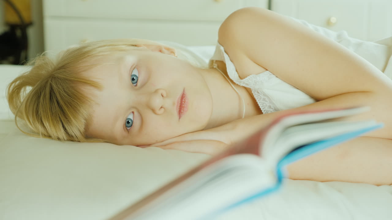 침대에서 책을 읽는 작은 금발 소녀 4k 비디오 28