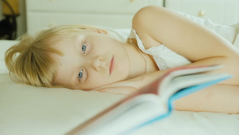 niña rubia leyendo un libro en la cama 4k video 28