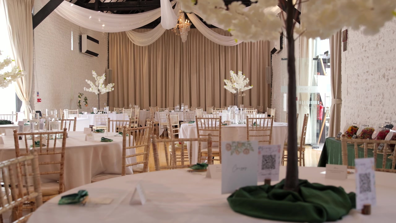 Toma de seguimiento a través de un salón de bodas con decoración floral blanca y sillas