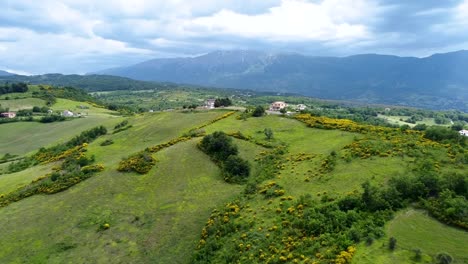 Aerial-shot-of-a-vast-mountain-landscape-with-a-house-and-a-motorcycle-passing