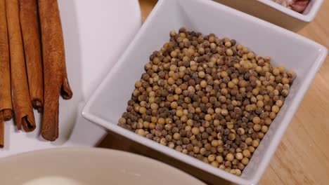 White-Pepper-in-Bowl-with-Cinnamon-on-White-Plate,-Close-Up