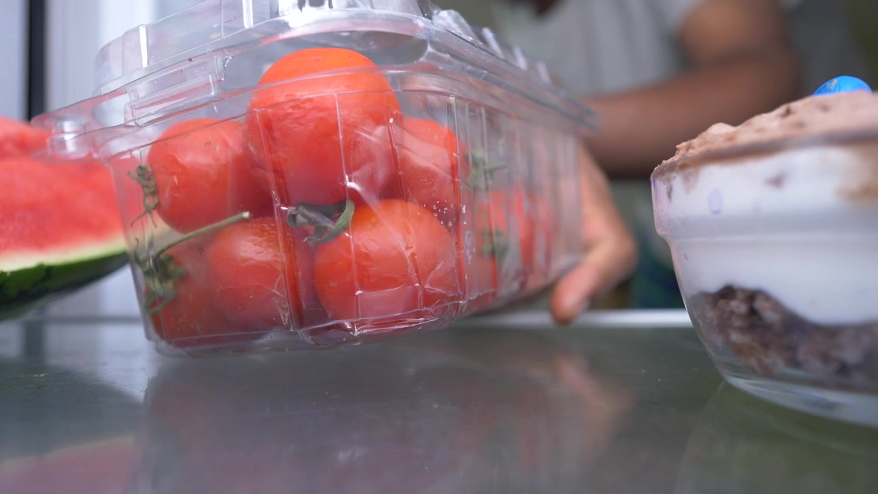 Person Removing Container of Fresh Tomatoes from Refrigerator