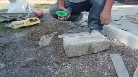 close up shot of workman using electric angle grinder with sharp circular blade disc for cutting ceramic tile on construction site, builder without protective gloves cutting ceramic tile with grinder