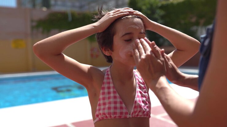 Mother applies sunscreen to her daughter on her face