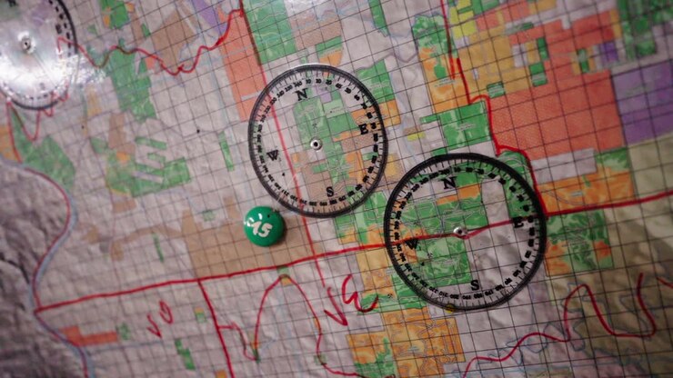 Close-up of a topographical map with compass and marker placed on it for navigation.
