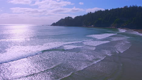 Aerial-flying-forward-near-shore-over-sand,-ocean-waves