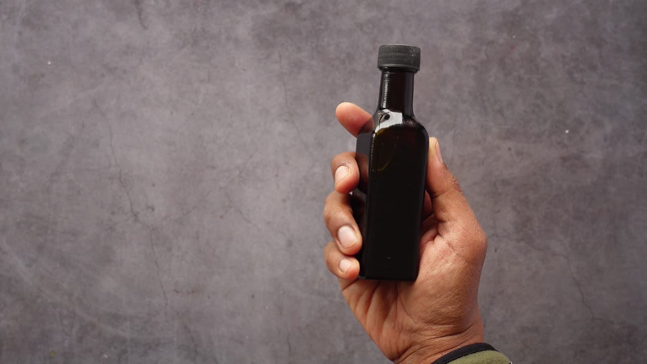 Hand holding a small dark glass bottle