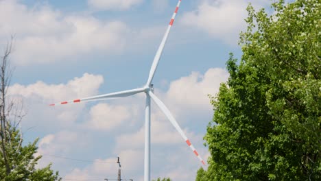 Renewable-energy-source,-wind-turbine-rotating-on-a-sunny-but-cloudy-day,-static