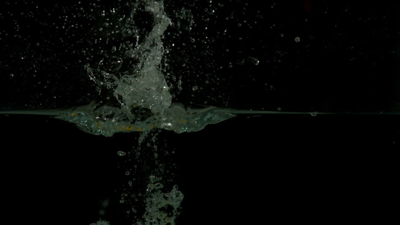 limón sumergiéndose en el agua sobre un fondo negro