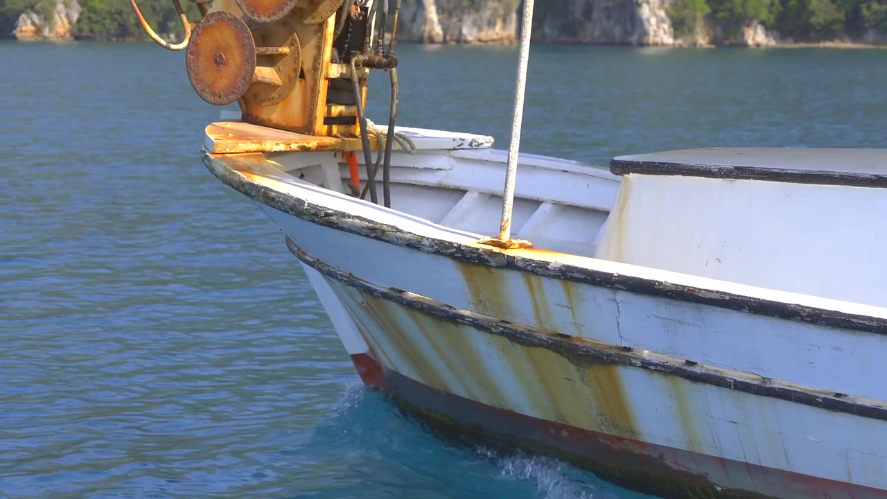 Primo piano della prua di una barca da pesca che solca acque calme