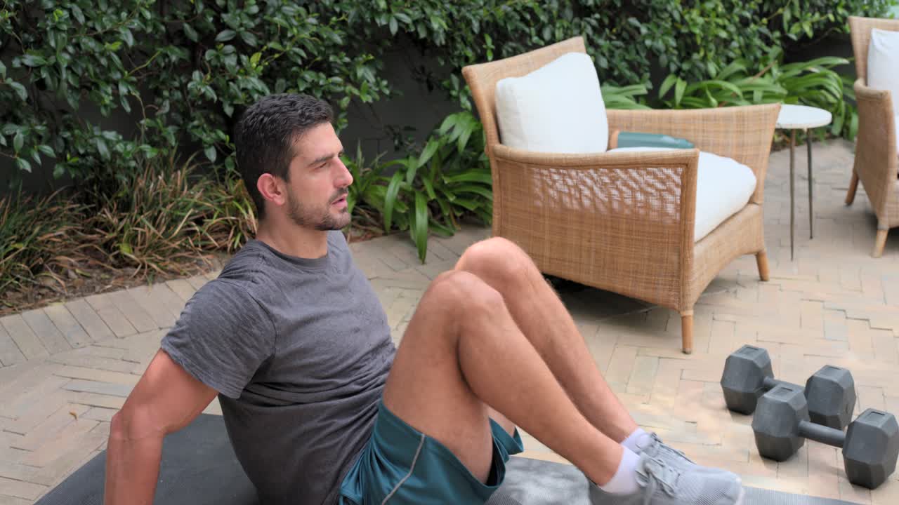Uomo che esegue pulsazioni delle gambe su un tappetino, sollevando i piedi e coinvolgendo gli addominali inferiori per il fitness, con la telecamera che si avvicina.