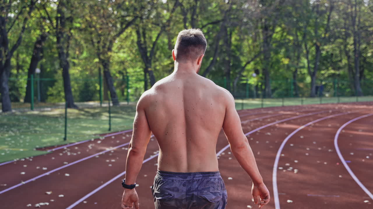 Handsome man at the stadium. Rear view of naked sportsman at stadium