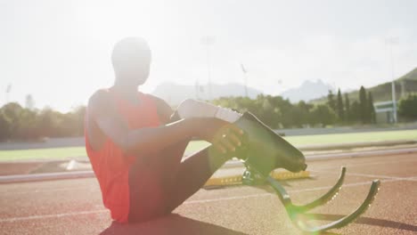 Disabled-mixed-race-man-with-prosthetic-legs-sitting-on-racing-track