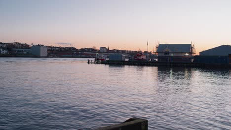 fishing boat heading back into port at sunset in north shields, england, followed by a flock of seabirds