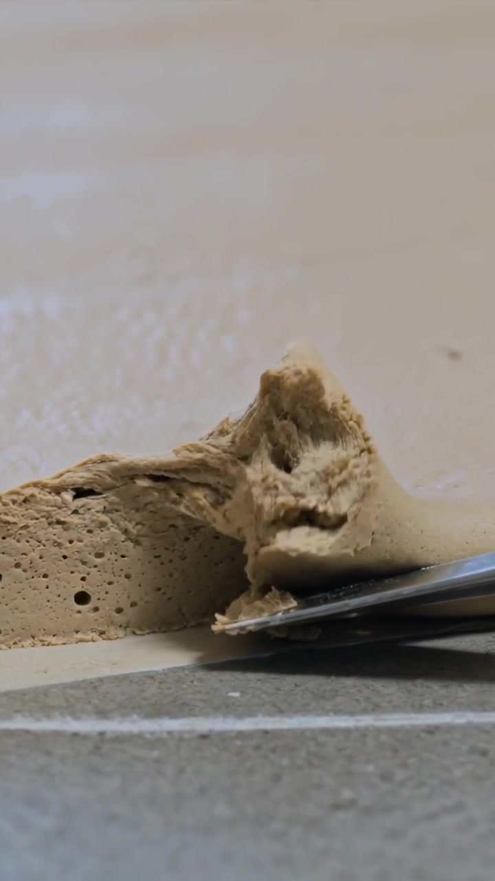 Vertical video: Prying metal scraper under seam, peeling beige caulk from wall joint to clear seal