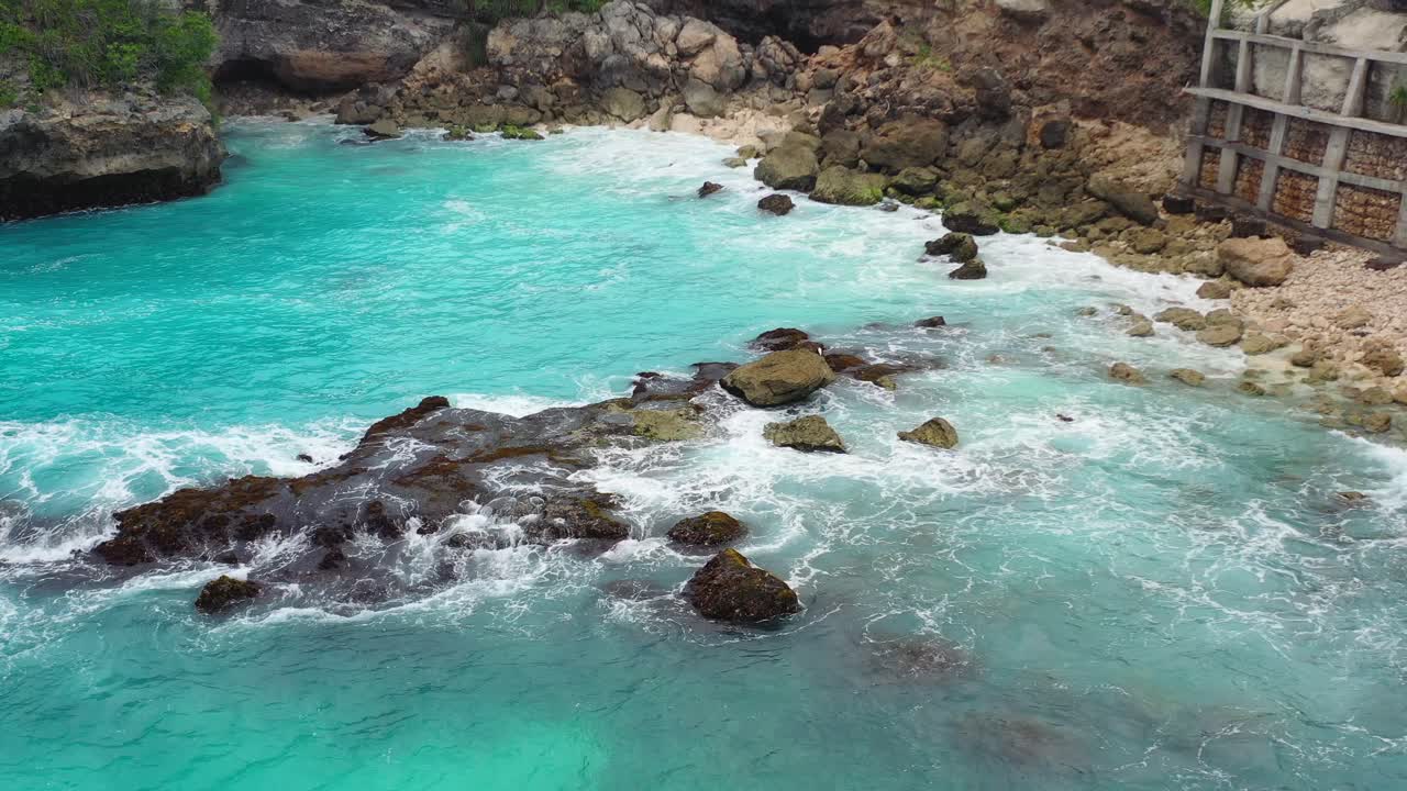 Onde tropicali pericolose che si infrangono sulla costa rocciosa alla Laguna Blu a Nusa Ceningan, vista aerea