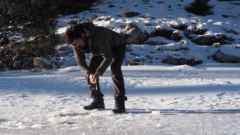 hombre rompiendo un hacha en un agujero de hielo