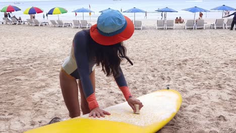 mujer preparando una tabla de surf en una playa tropical