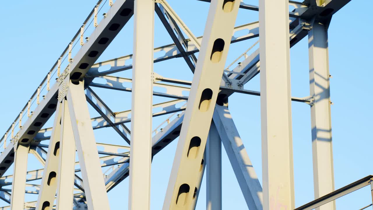 Steel bridge structure with rivets and beams under bright blue sky, for train crossing