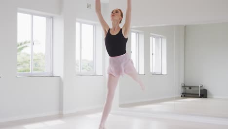 caucasian female ballet dancer practicing ballet during a dance class in a bright studio