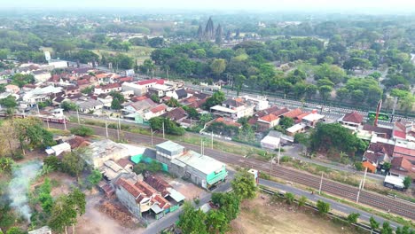 aerial view of a train passing through a village near a temple in indonesia