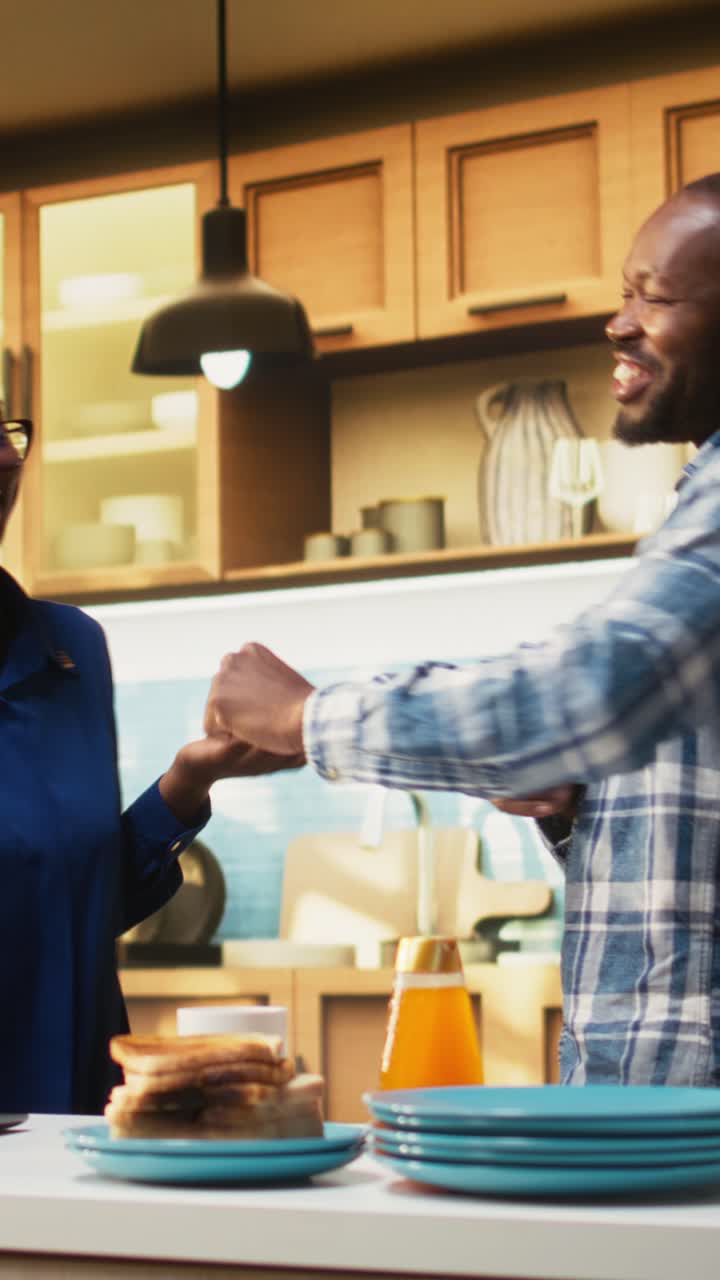 Vertical Video Black couple doing dance moves and laughing in their bright kitchen