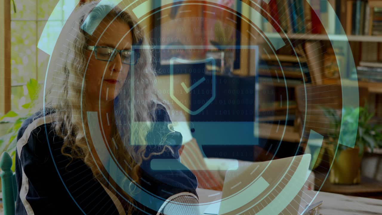 Femme mûre tapant sur un ordinateur portable, soulevant un smartphone et activant un bouclier holographique de sécurité technologique