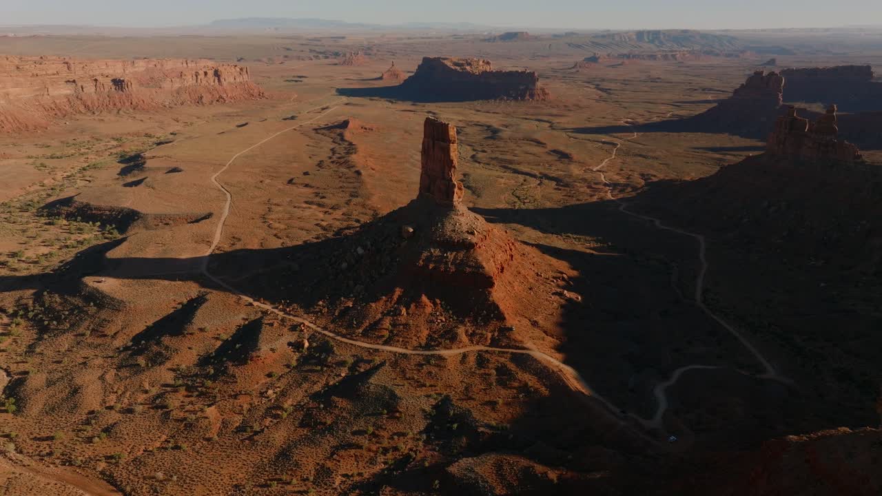 Wide aerial of sandstone spire and surrounding desert mesas in Valley of the Gods Utah, drone tilt up, nobody