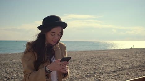 mujer en la playa usando el teléfono