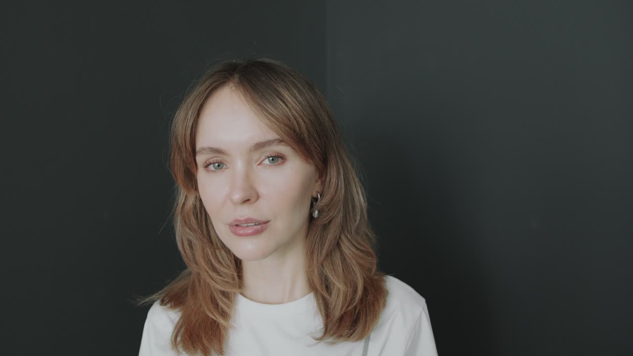 Portrait of Young Pretty Woman against Dark Studio Background