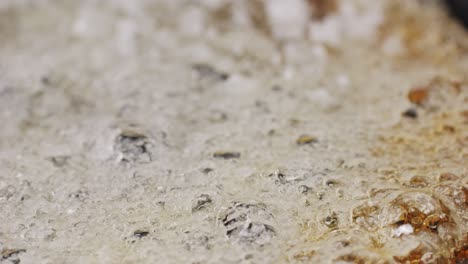 close up of boiling sugar with bubbles turns into caramel, caramelization, chef cooking dessert in cafe, restaurant pastry food.