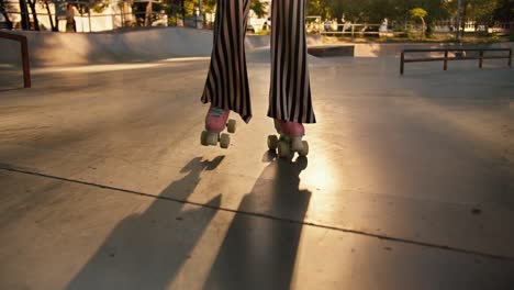 una chica con un corte de pelo corto en una camiseta púrpura, pantalones a rayas y auriculares rojos bailando en un skatepark al atardecer en verano