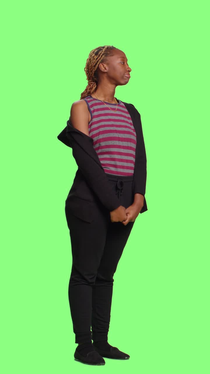 Video verticale: ragazza afroamericana in piedi su green screen a figura intera