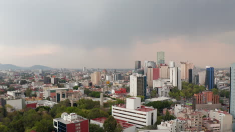 Vista-Aérea-De-Gran-Variedad-De-Edificios-En-El-Centro.-Casas-Coloridas-Alternando-Con-árboles-Verdes.-Cámara-De-Drones-Voladores-Hacia-Atrás,-Cielo-Nublado-Antes-De-La-Lluvia.-Ciudad-De-México,-México.