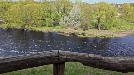 Wooden-guard-rail-and-flowing-river-bellow,-motion-view